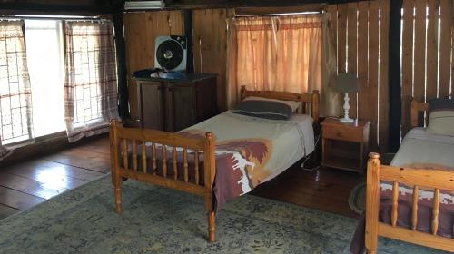 a bedroom with two beds in a room with wooden walls at Toad Tree Cabins in Sodwana Bay