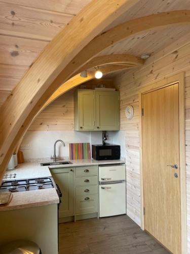 a kitchen with an arched ceiling in a log cabin at Hedgehog Glamping Pod School House Farm in Leighton