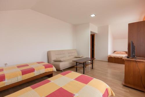 a room with two beds and a couch and a television at Guesthouse Capistro in Bilje