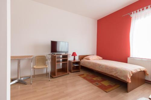 a bedroom with a bed and a desk and a television at Guesthouse Capistro in Bilje