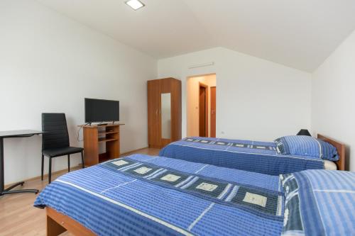two beds in a room with a desk and a television at Guesthouse Capistro in Bilje
