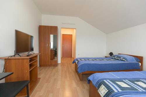 a hotel room with two beds and a flat screen tv at Guesthouse Capistro in Bilje