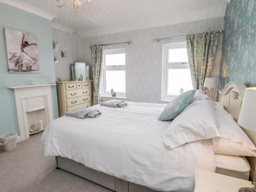 a bedroom with a large white bed and two windows at 7 Marine Drive in Hartlepool