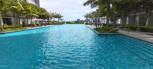 un bassin d'eau bleue avec des palmiers et des bâtiments dans l'établissement Cyberjaya cybersqure peace home, à Cyberjaya