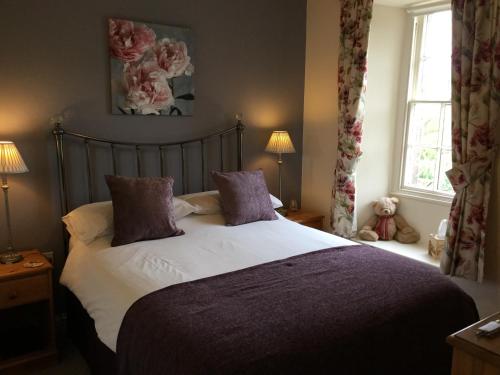 a bedroom with a bed with purple pillows and a window at Crown Cottage Farm in Skipton