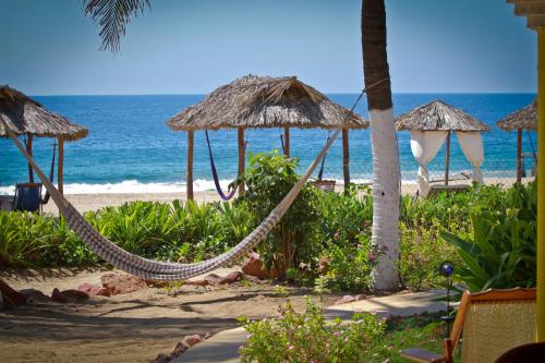 a hammock on a beach with the ocean at Hotel Gilda in Coyuca