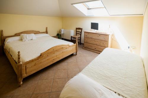 a bedroom with two beds and a dresser and a television at L'Incanto dei Sibillini in Cessapalombo