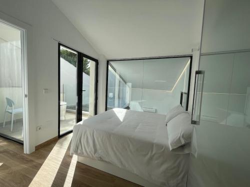 a bedroom with a white bed and large glass windows at Casa rural - bungalows Spa & Relax in La Felipa