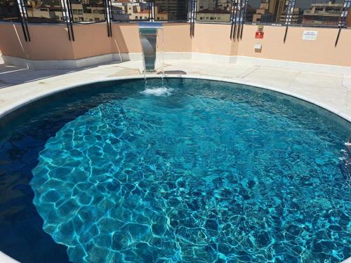 a large swimming pool with a water fountain at Cosmopolitan Praia Flat in Santos