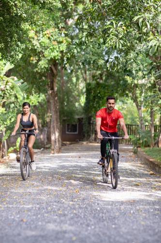 a man and a woman riding bikes down a street at Kalu's Hideaway Udawalawe in Udawalawe
