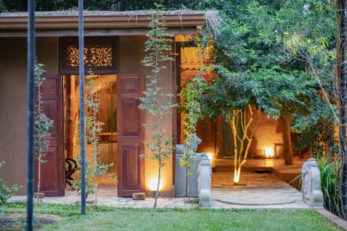 a house with a wooden door in the yard at Kalu's Hideaway Udawalawe in Udawalawe