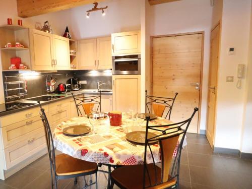 une cuisine avec une table et des chaises et une cuisine avec des placards blancs dans l'établissement Appartement récent, 3e étage, exposé Sud-Est, à 10mn des pistes, balcon, parking et casier à skis - FR-1-623-199, aux Gets