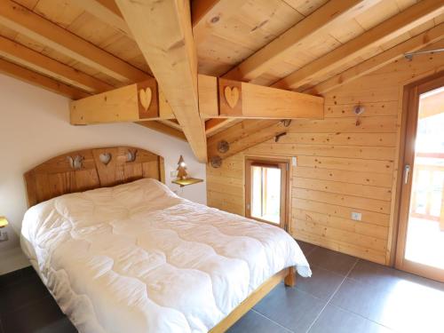 - une chambre avec un grand lit dans une maison en bois dans l'établissement Appartement récent, 3e étage, exposé Sud-Est, à 10mn des pistes, balcon, parking et casier à skis - FR-1-623-199, aux Gets