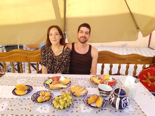 a man and a woman sitting at a table with food at Imran&Bek in Samarkand