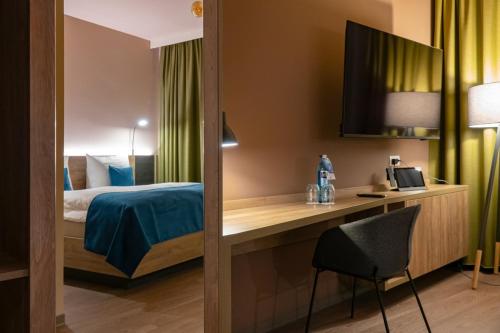 een slaapkamer met een bed en een bureau met een stoel bij H24 Stadthotel Bernau in Bernau bei Berlin