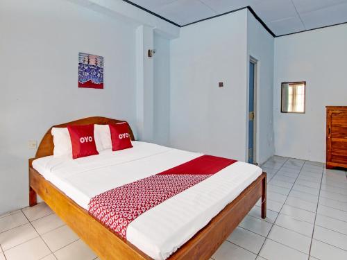 a bedroom with a bed with red pillows on it at Capital O 91644 Loka Hause in Salatiga