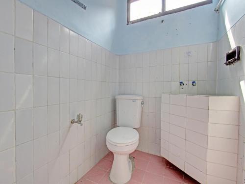 a bathroom with a white toilet and a window at Capital O 91644 Loka Hause in Salatiga