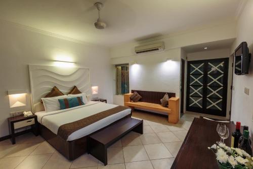 a bedroom with a king sized bed and a couch at Sonesta Inns Beach Resort - Candolim Beach in Candolim