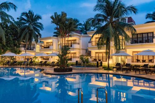 un hôtel avec une piscine en face d'un bâtiment dans l'établissement Sonesta Inns Beach Resort - Candolim Beach, à Candolim