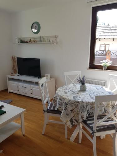 a living room with a table and a tv and a window at Vila Irina Kopaonik in Kopaonik