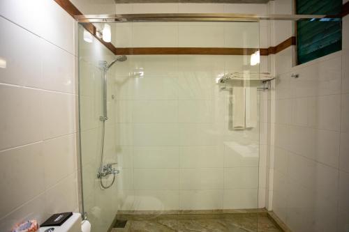 a shower with a glass door in a bathroom at Kalu's Hideaway Udawalawe in Udawalawe