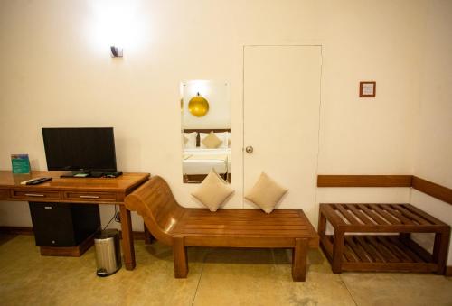 a room with a desk with a computer and a bench at Kalu's Hideaway Udawalawe in Udawalawe