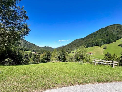a grassy field with a wooden fence and mountains at Ferienwohnung Alpenglück in Marktschellenberg