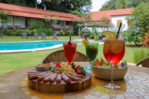 una mesa con una bandeja de comida y dos bebidas en Hotel Fazenda Bela Vista, en Dourado