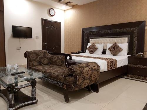 a bedroom with a bed and a chair and a table at Hotel Visit Inn One in Lahore