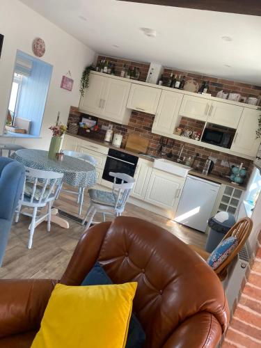 a living room with a leather couch and a kitchen at Toddys Cottage & Stables in Cavan