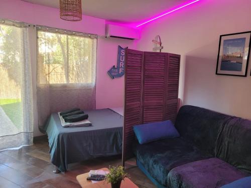 salon z kanapą i różowym światłem w obiekcie Parking privé + Jardin + Clim proche Plage & Resto w Cagnes-sur-Mer