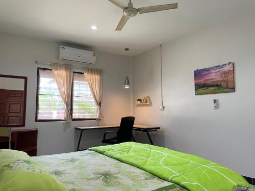 Schlafzimmer mit einem Bett, einem Schreibtisch und einem Deckenventilator in der Unterkunft H&Q 1BR Cozy House, Bangtao Beach in Ban Thalat Choeng Thale