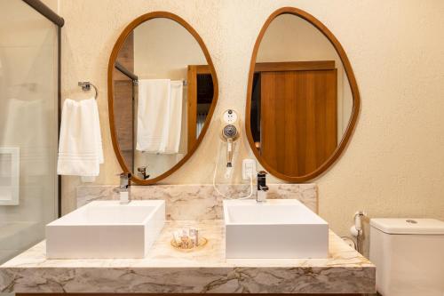 a bathroom with two sinks and two mirrors at Hotel Vivenda dos Sonhos in Gramado