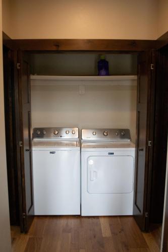 two washing machines in a small kitchen with a shelf at Glacier Homestead in Coram
