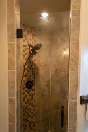 a shower with a glass door with a shower head at Glacier Homestead in Coram