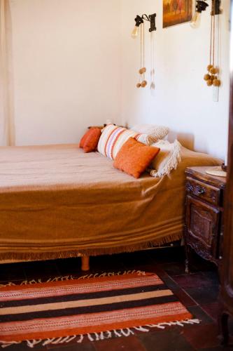 a bed with orange pillows on it in a room at Estancia Rio de Arena in Colalao del Valle