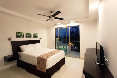 a bedroom with a bed and a flat screen tv at Oceano Boutique Hotel & Gallery in Jacó