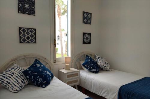 2 camas con almohadas azules y blancas en una habitación en Apartamento Son Parc Menorca, en Son Parc