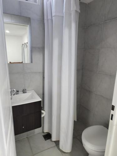 La salle de bains est pourvue d'un rideau de douche blanc et de toilettes. dans l'établissement Monoambiente en el centro de la Ciudad., à Mercedes