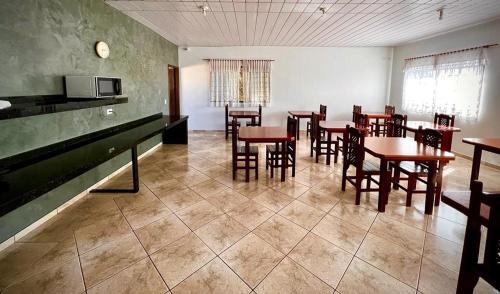 a dining room with tables and chairs and a kitchen at Residence Hotel Ltda in Paiçandu