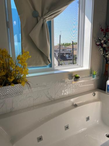 a white bath tub in a bathroom with a window at Six minutes to Rupert station in Vancouver