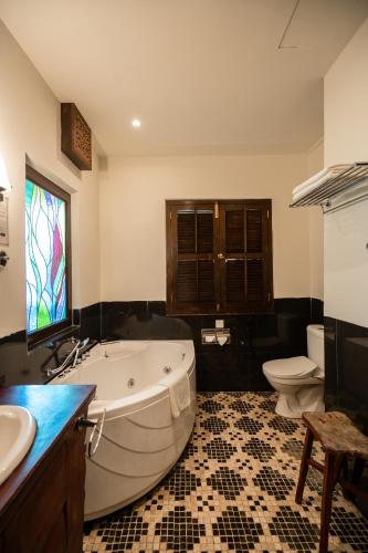 a bathroom with a tub and a toilet and a sink at Hotel Penaga in George Town