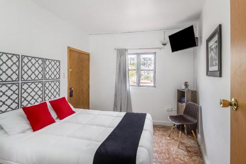 Un dormitorio con una cama con almohadas rojas y una ventana en Hotel La Colección, Universidad de Guanajuato, Centro en Guanajuato