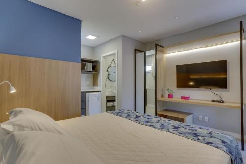 a bedroom with a bed and a flat screen tv at Hotel Sete Ilhas in Florianópolis