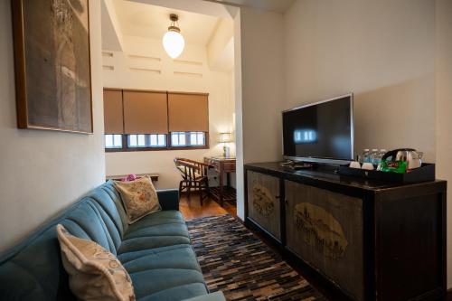 a living room with a blue couch and a flat screen tv at Hotel Penaga in George Town