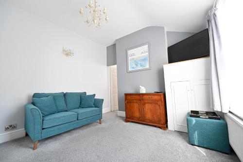 a living room with a blue couch and a dresser at Avoncot Guest House in Stratford-upon-Avon