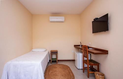 a bedroom with a bed and a tv on the wall at Pousada Altamira in Ilhabela