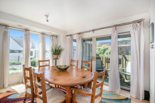 a dining room with a wooden table and chairs and windows at Hoopdee Scootee Suite in Saugatuck
