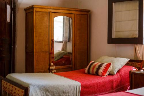 a bedroom with a mirror and a bed with a red blanket at Estancia Rio de Arena in Colalao del Valle