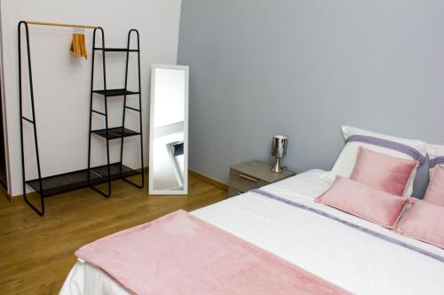 1 dormitorio con cama con almohadas rosas y espejo en F2 Duplex chez l'aventurière près Disneyland, en Roissy-en-Brie